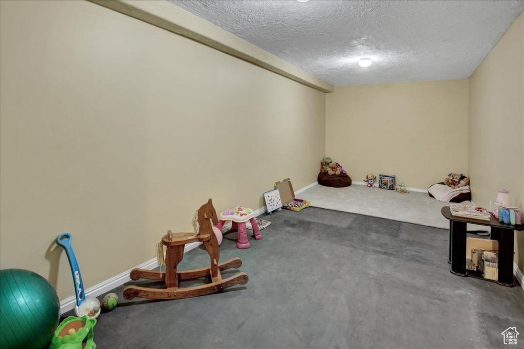 Playroom featuring a textured ceiling, baseboards, and carpet