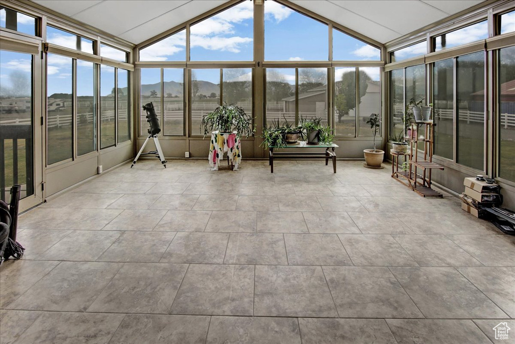 Sunroom / solarium with healthy amount of natural light, vaulted ceiling, and a mountain view