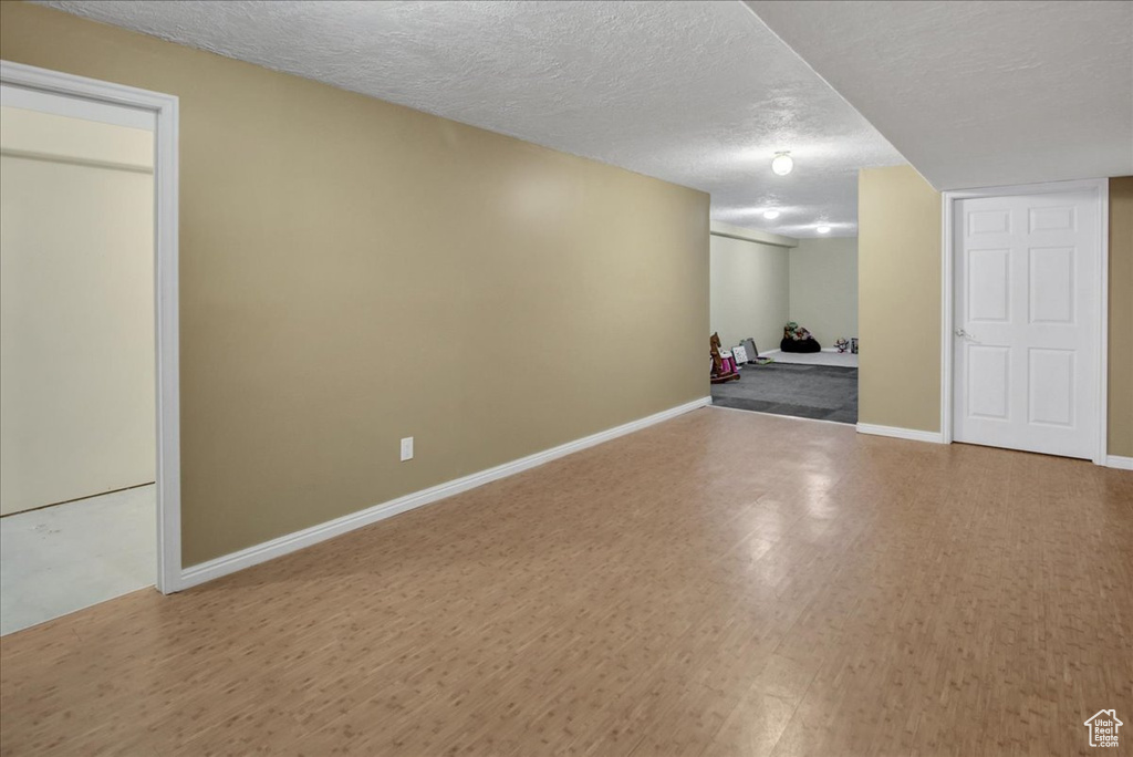 Finished below grade area featuring wood finished floors, a textured ceiling, and baseboards