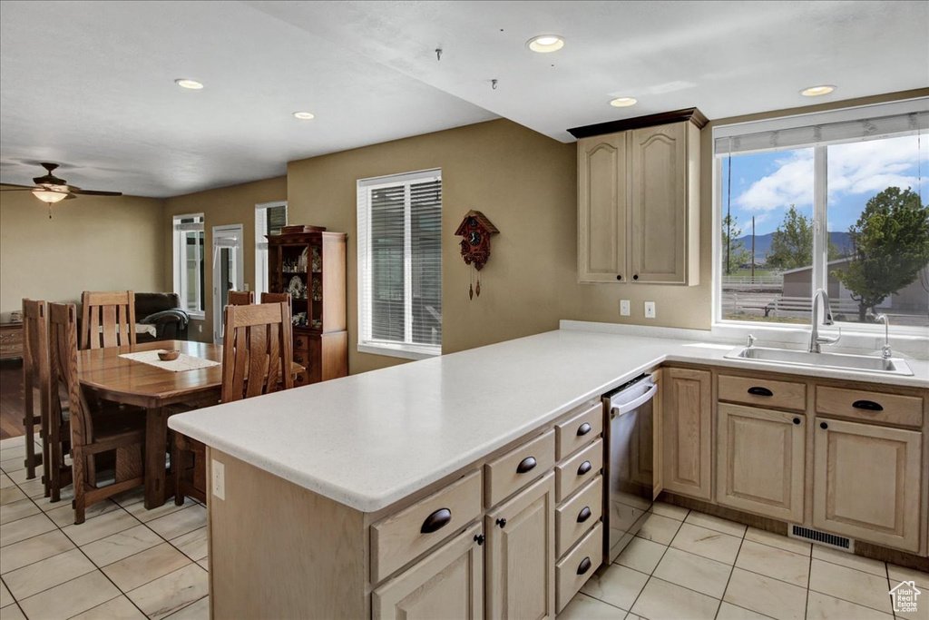 Kitchen with a sink, stainless steel dishwasher, ceiling fan, light countertops, and light brown cabinets