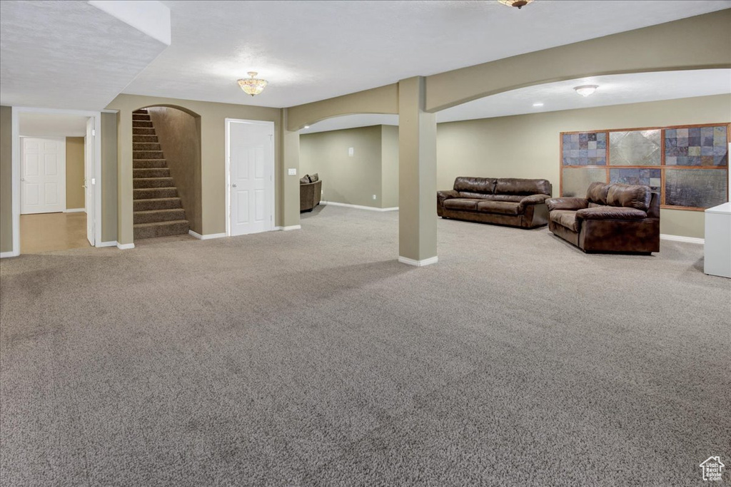 Carpeted living area with arched walkways, stairs, and baseboards