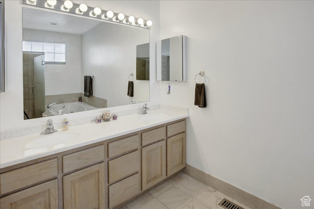 Full bathroom with a bath, marble finish flooring, double vanity, baseboards, and a shower stall