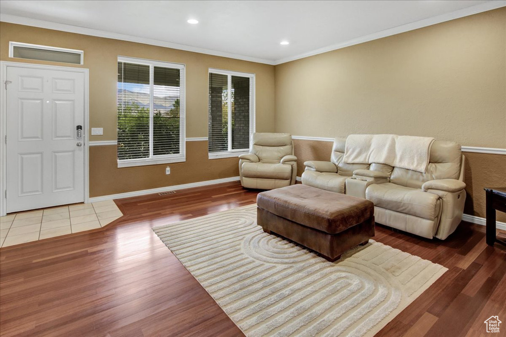 Living room with wood finished floors, crown molding, baseboards, and recessed lighting