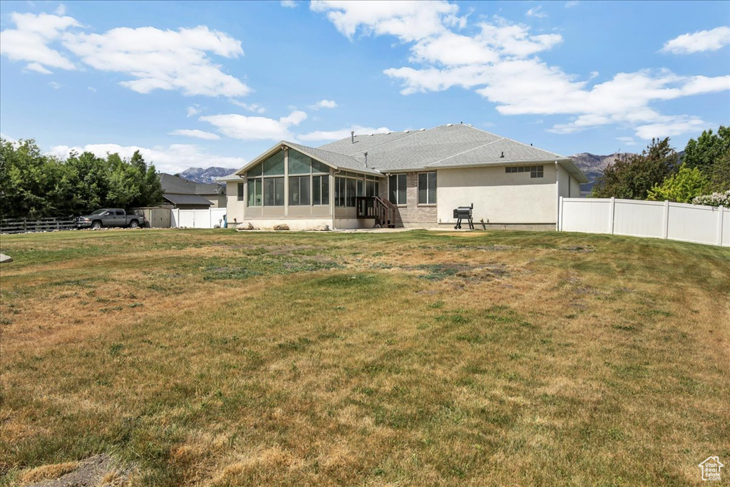 Rear view of house featuring a sunroom and stucco siding