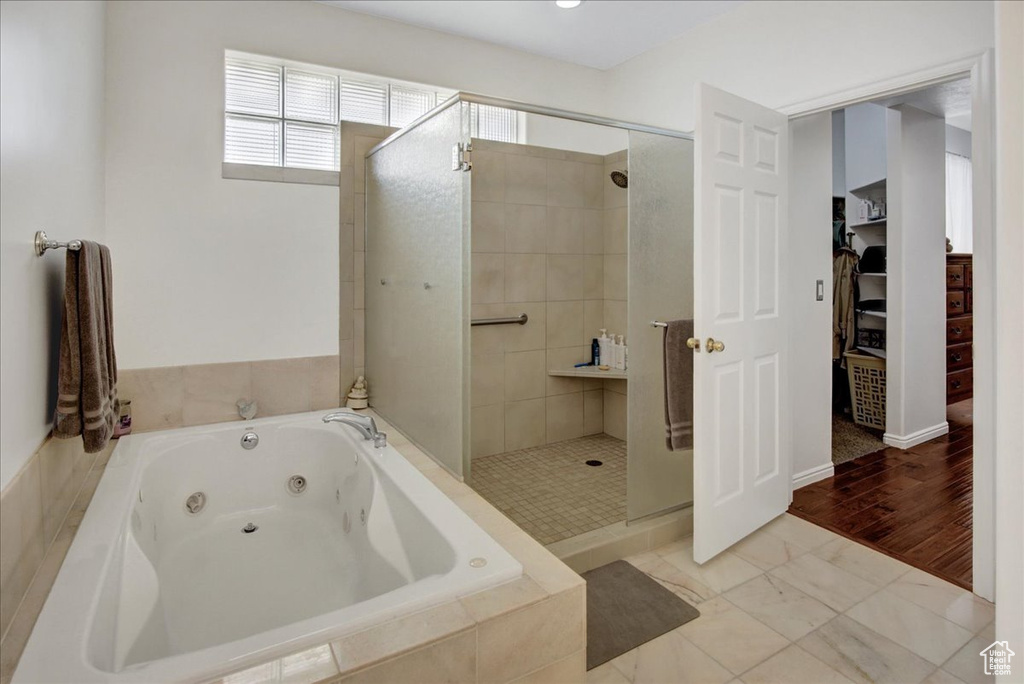 Full bath featuring a shower stall, a tub with jets, and a walk in closet