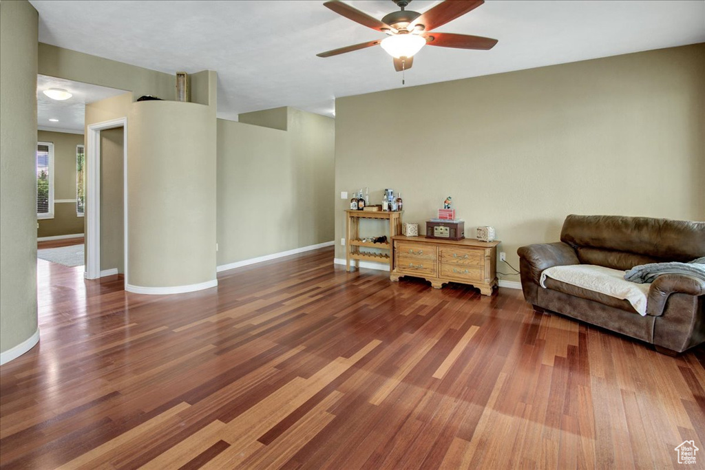 Living area featuring a ceiling fan, wood finished floors, and baseboards