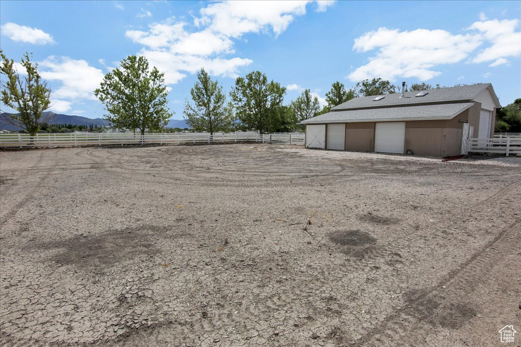 View of yard with a detached garage, fence, an outdoor structure, a mountain view, and a rural view