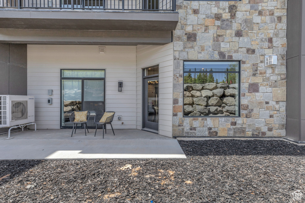 Entrance to property with a balcony, ac unit, and stone siding