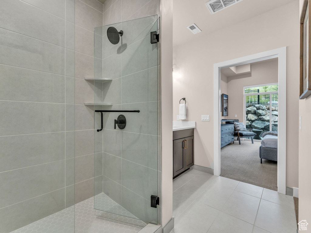 Ensuite bathroom featuring a shower stall, tile patterned flooring, and baseboards
