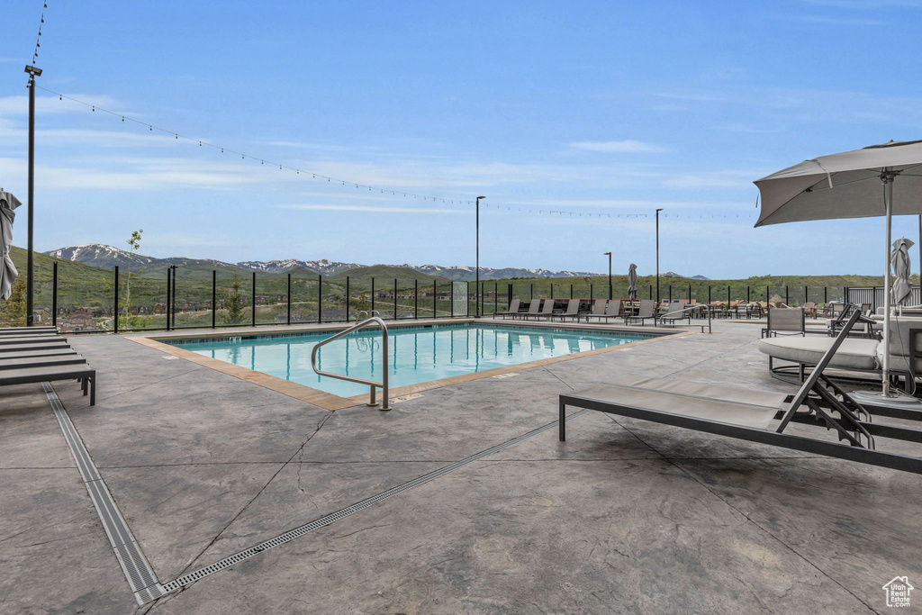 Community pool with fence, a patio area, and a mountain view