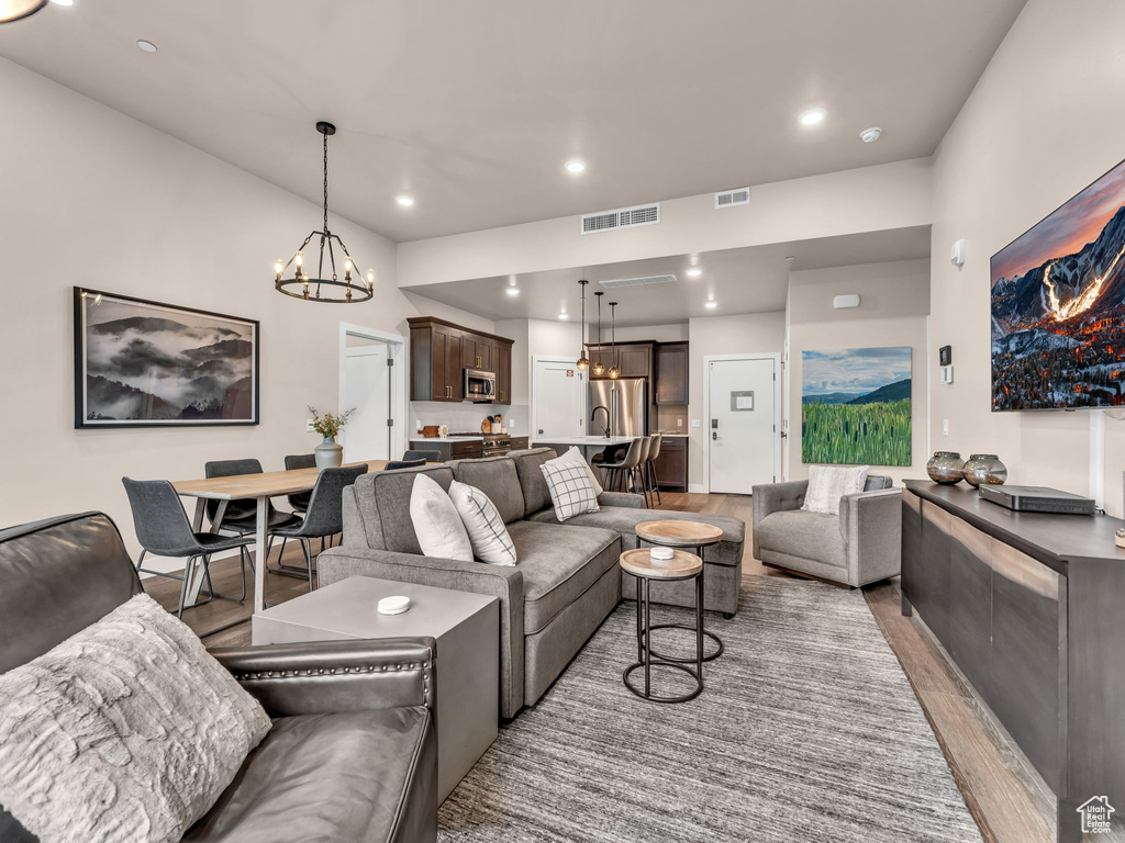 Living area with light wood-type flooring, a chandelier, and recessed lighting