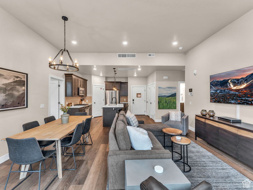 Living room featuring wood finished floors, a chandelier, baseboards, and recessed lighting