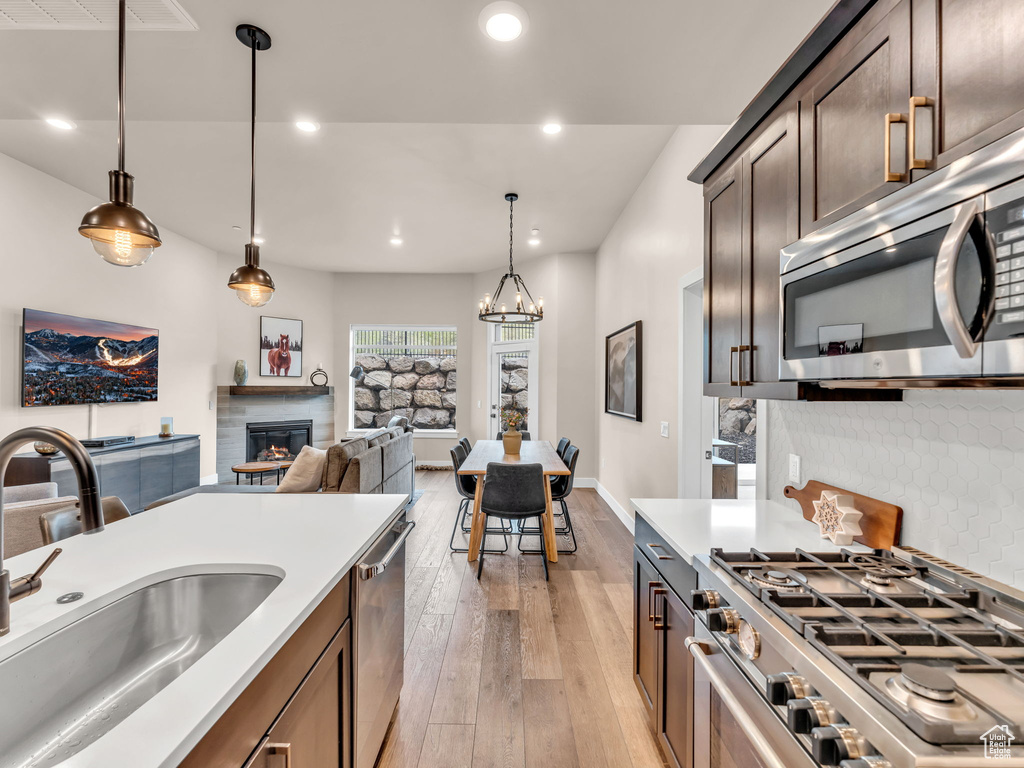 Kitchen featuring stainless steel appliances, a sink, light wood-type flooring, recessed lighting, and decorative light fixtures
