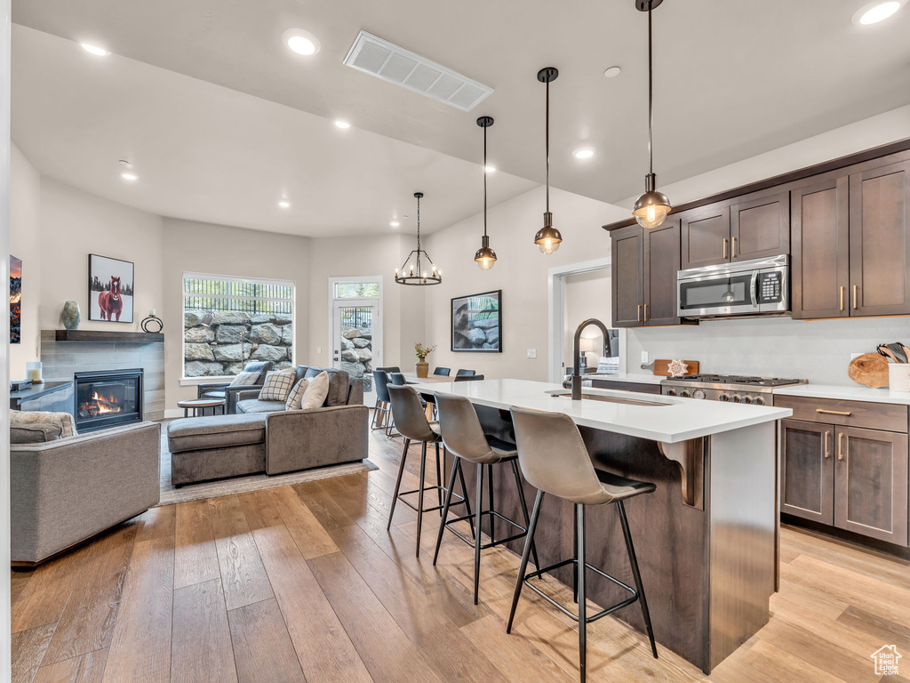 Kitchen featuring stainless steel microwave, a sink, a kitchen breakfast bar, open floor plan, and a center island with sink