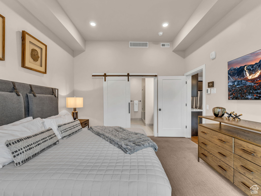 Bedroom featuring light carpet, recessed lighting, and a barn door