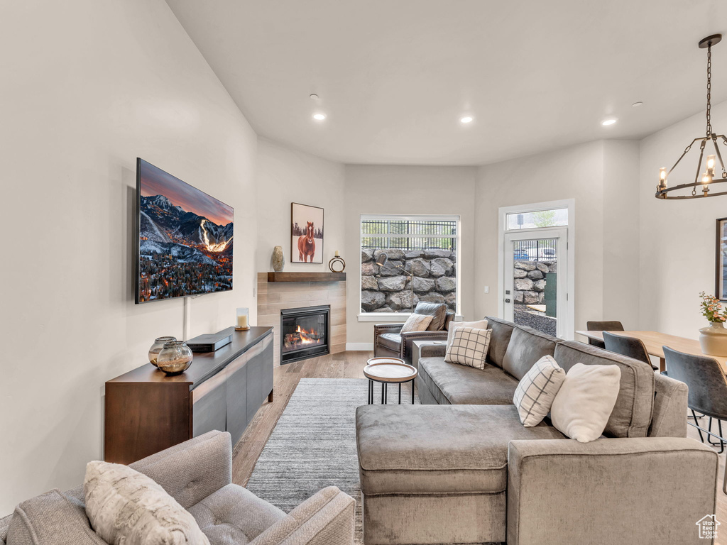 Living room featuring light wood-style flooring, recessed lighting, a chandelier, and a glass covered fireplace