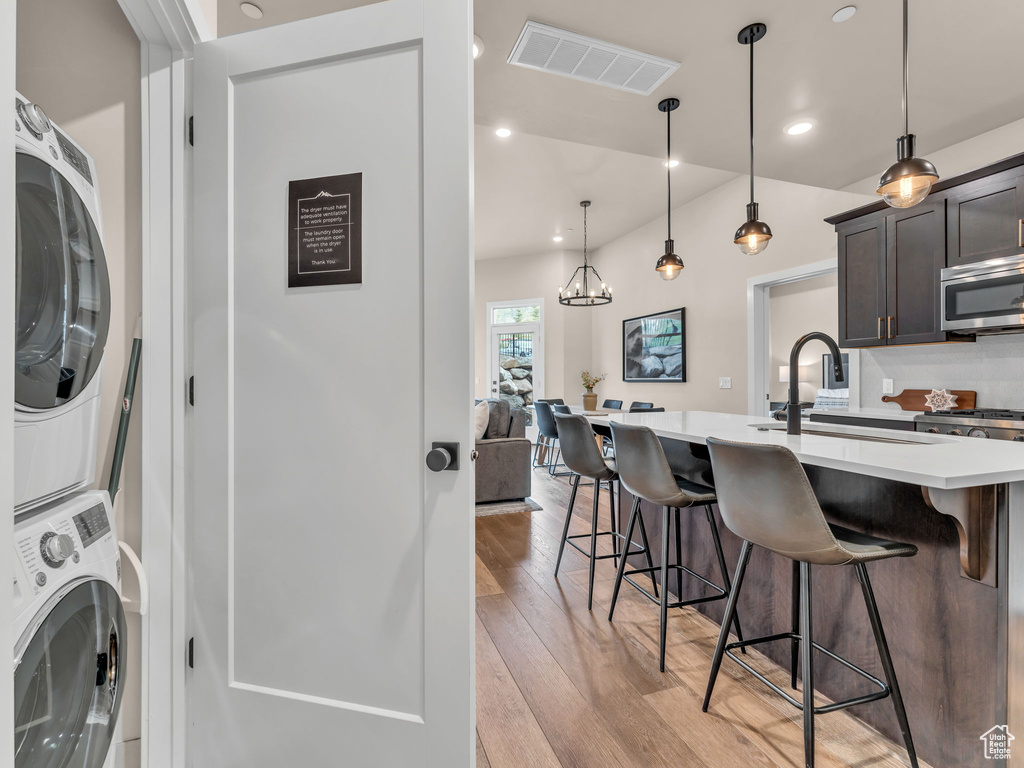 Washroom featuring stacked washer and clothes dryer, light wood finished floors, and recessed lighting