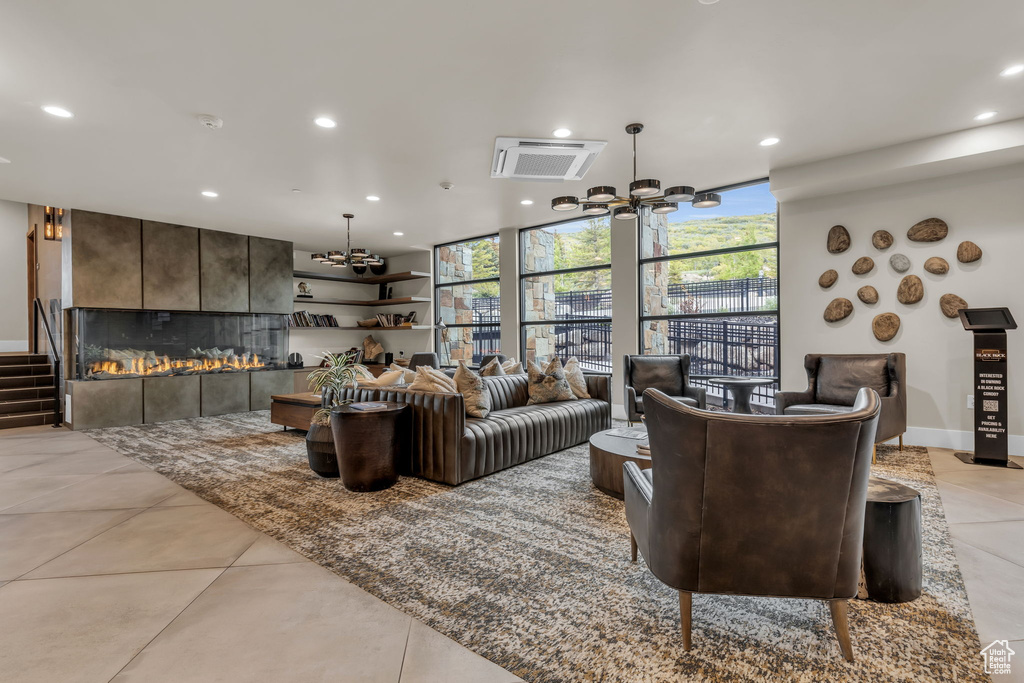 Living room with a chandelier, recessed lighting, a tile fireplace, a wall of windows, and light tile patterned floors