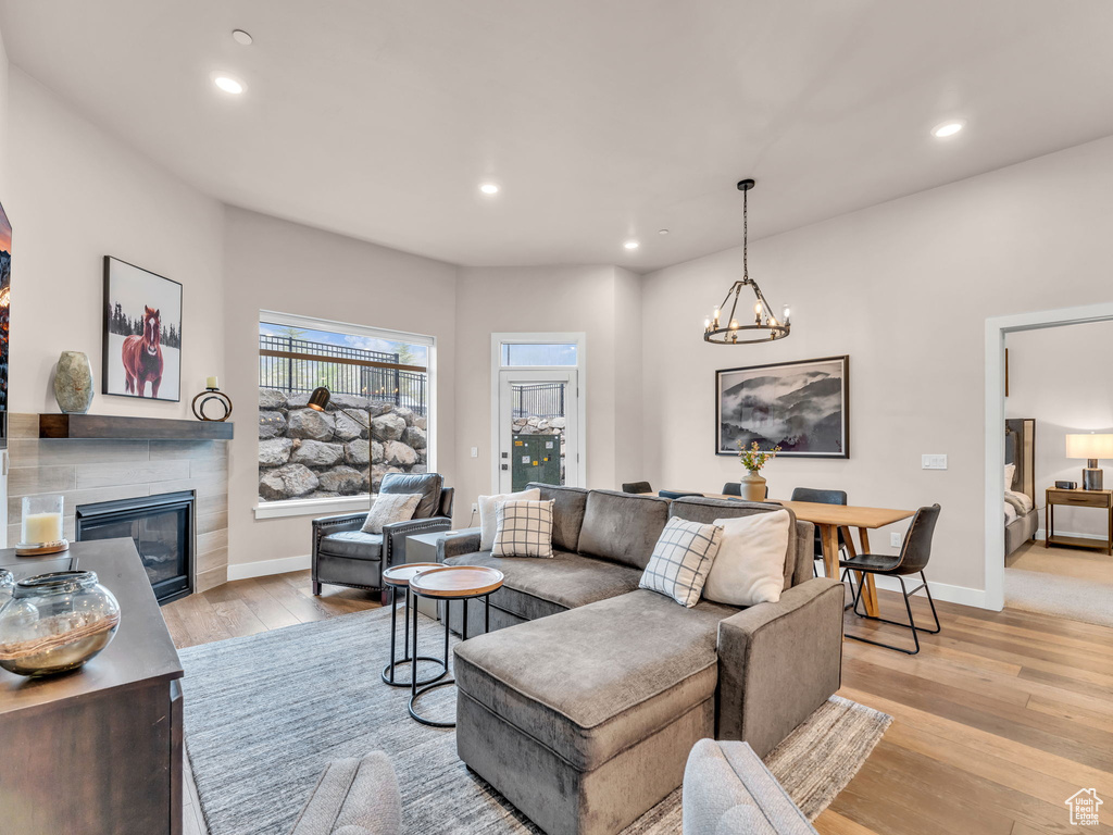 Living area featuring a tile fireplace, light wood finished floors, recessed lighting, baseboards, and a chandelier