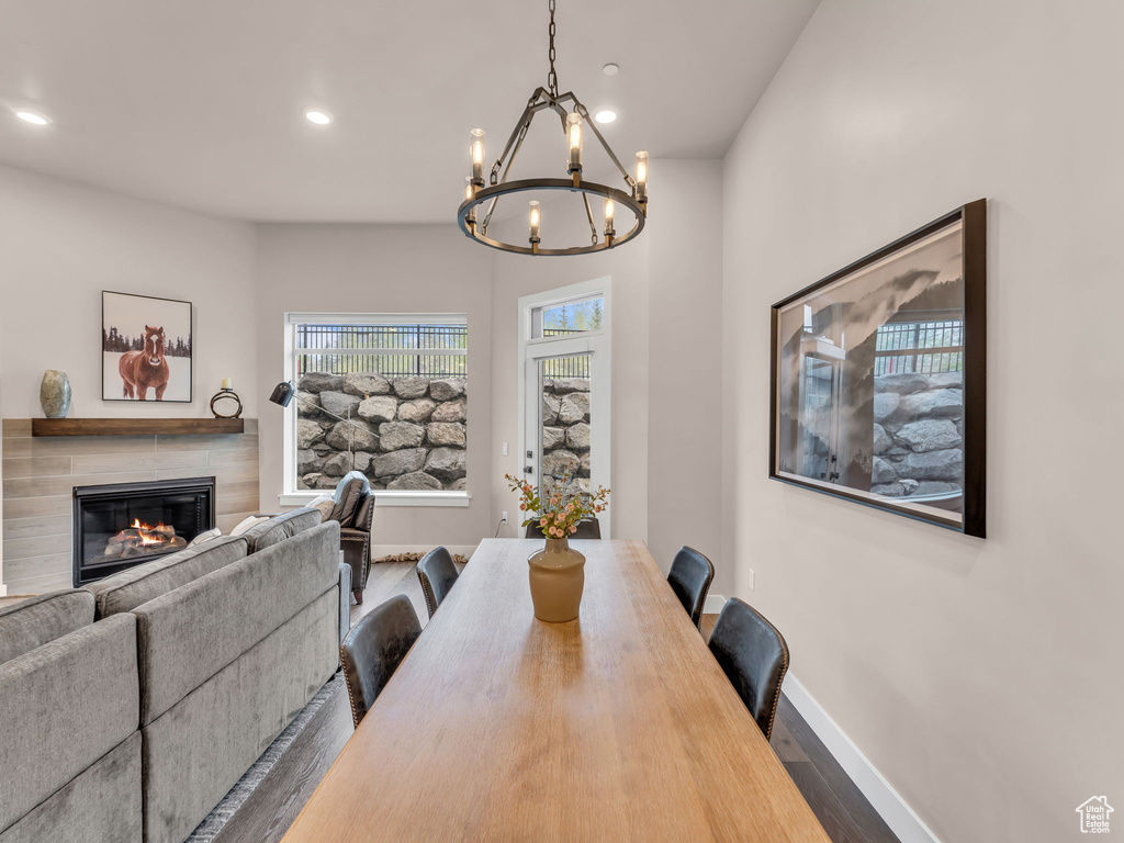 Dining area featuring dark wood-type flooring, a chandelier, a fireplace, recessed lighting, and baseboards