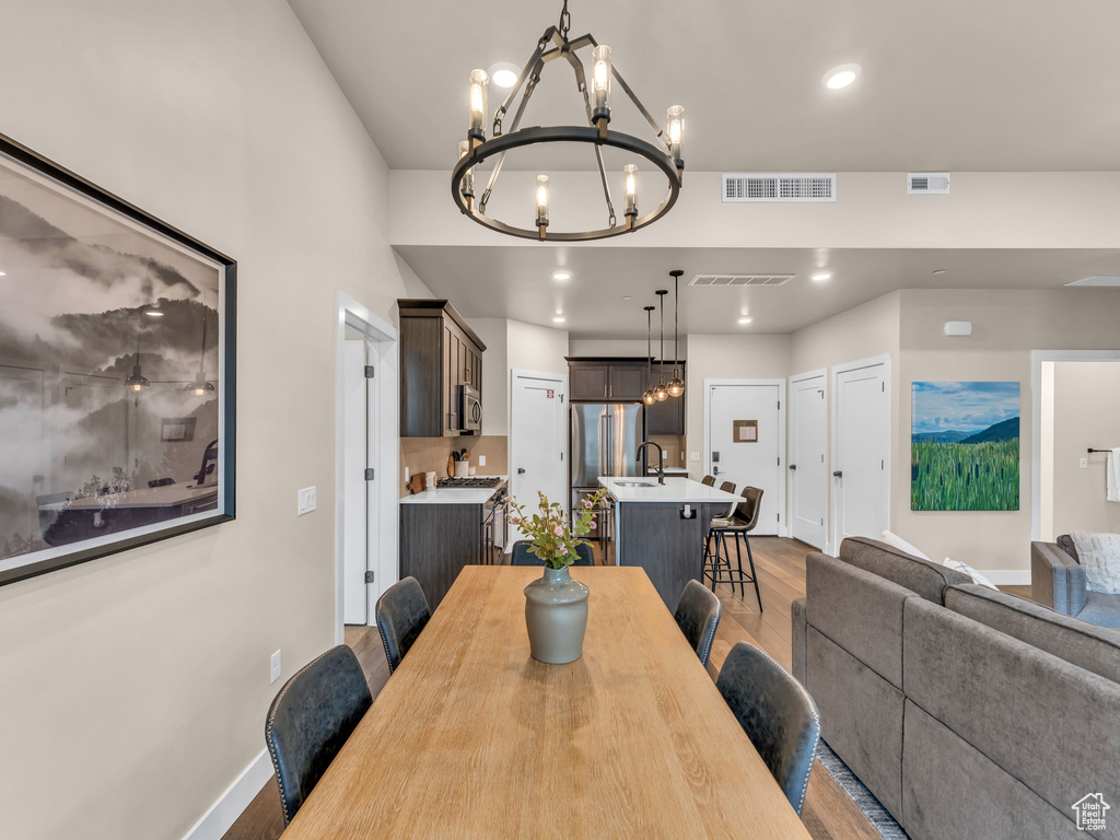 Dining room with a chandelier, light wood-style floors, baseboards, and recessed lighting