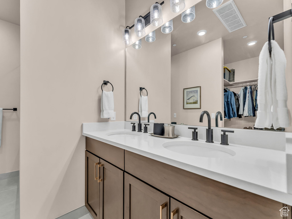 Bathroom featuring a walk in closet, double vanity, and recessed lighting