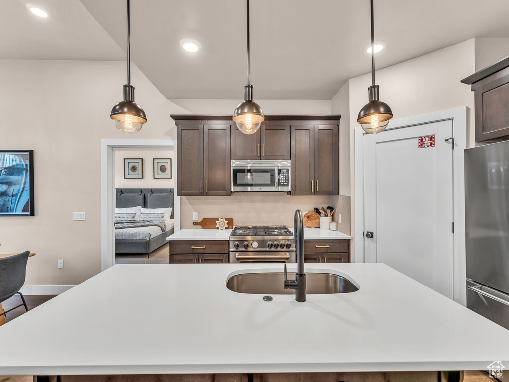 Kitchen featuring appliances with stainless steel finishes, a sink, light countertops, dark brown cabinets, and recessed lighting