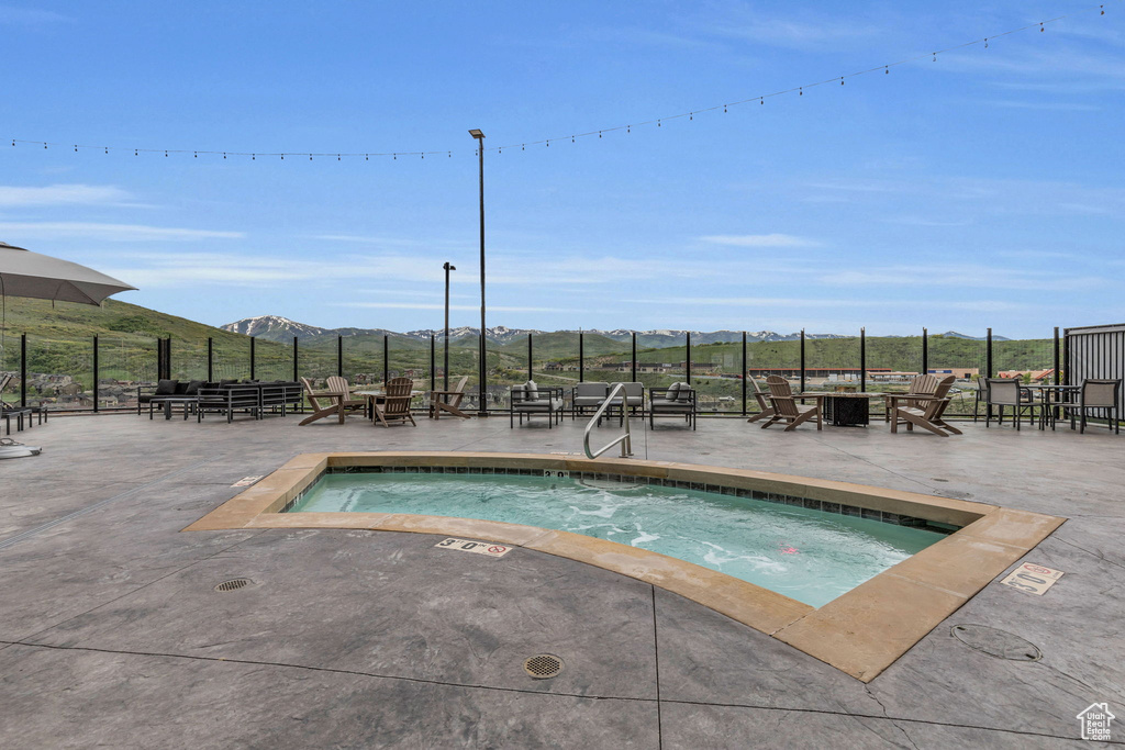 View of swimming pool with an outdoor fire pit, fence, a patio area, and a mountain view
