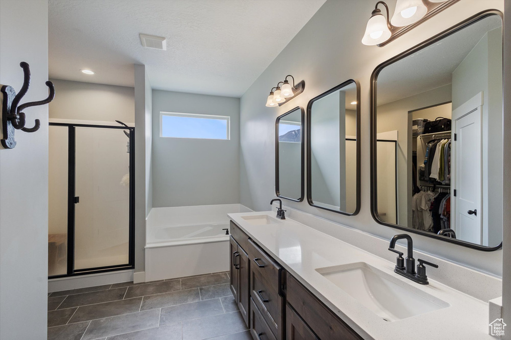 Bathroom with a stall shower, a bath, double vanity, a walk in closet, and recessed lighting