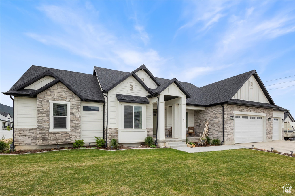 View of front of property featuring stone siding, driveway, board and batten siding, and a garage
