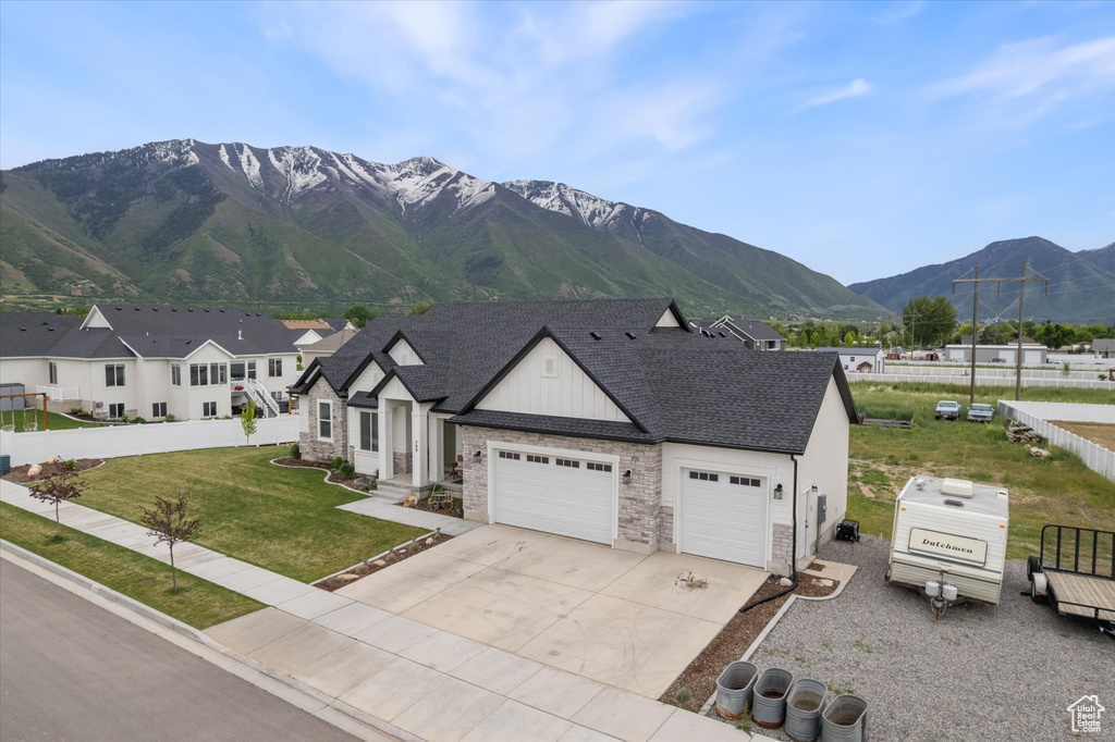 View of front of house with an attached garage, concrete driveway, stone siding, a mountain view, and board and batten siding