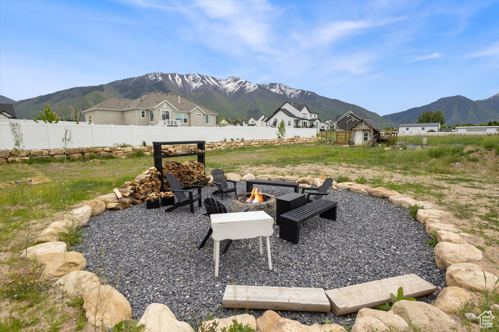 View of yard featuring a fire pit, a mountain view, fence, and a residential view