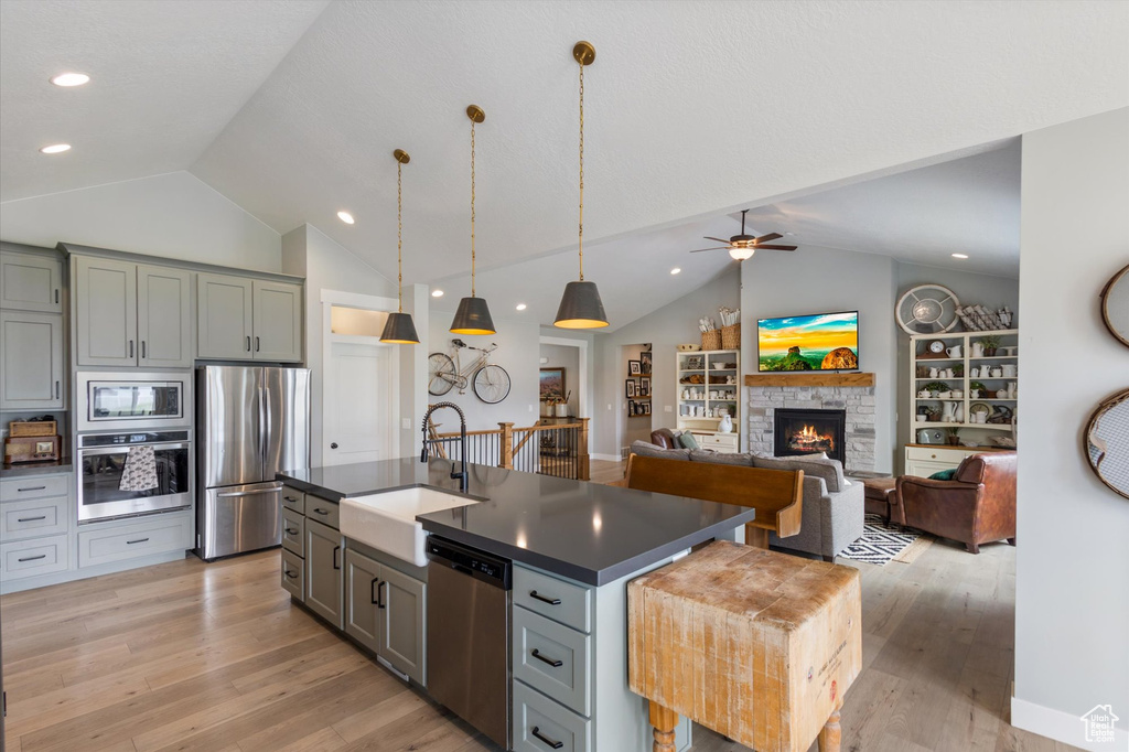 Kitchen with stainless steel appliances, vaulted ceiling, dark countertops, a sink, and a ceiling fan