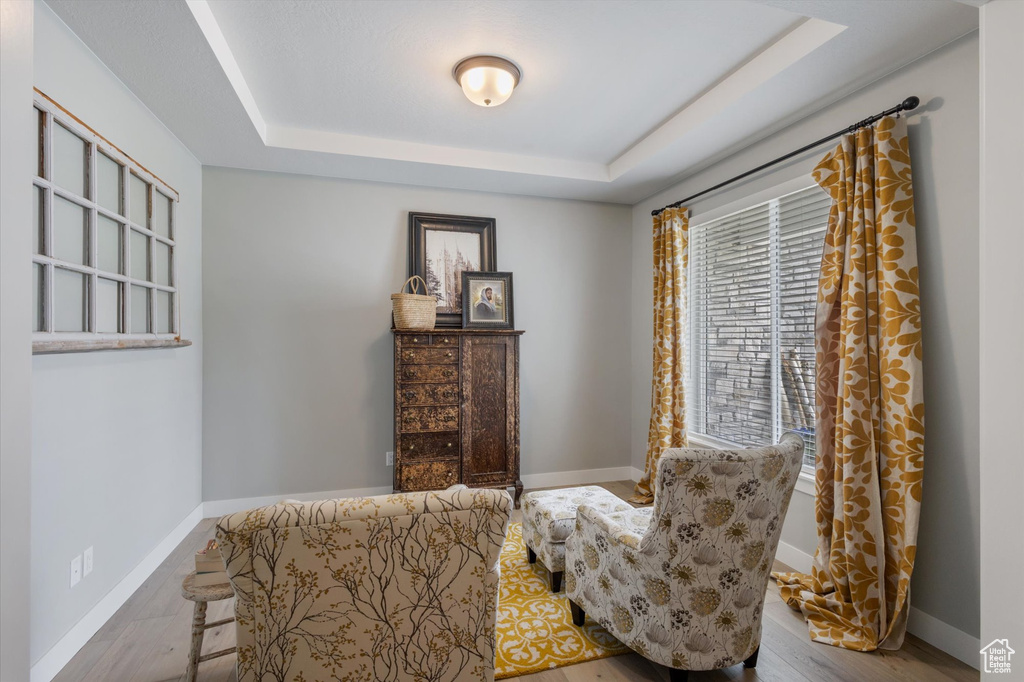 Sitting room with a raised ceiling, baseboards, and wood finished floors