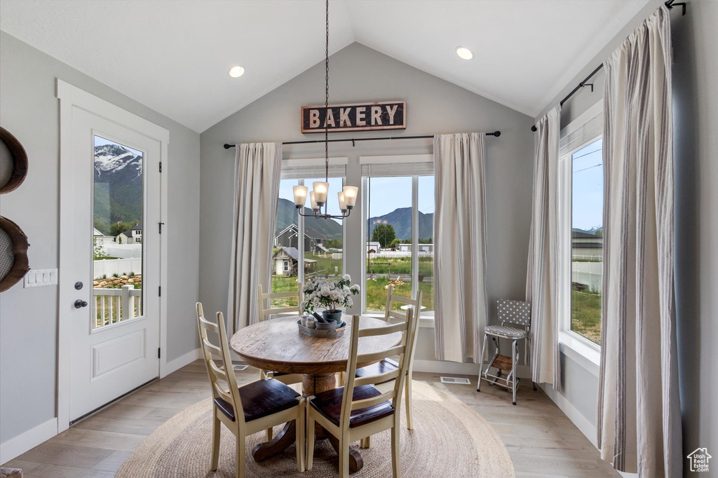 Dining room with a chandelier, lofted ceiling, light wood finished floors, recessed lighting, and a mountain view