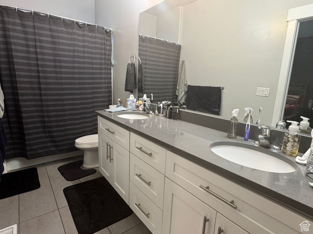 Full bath with tile patterned flooring, toilet, double vanity, and curtained shower