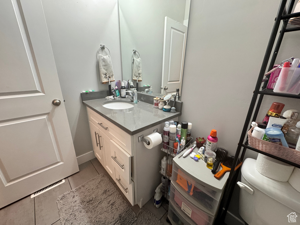 Half bath featuring vanity, tile patterned flooring, and toilet