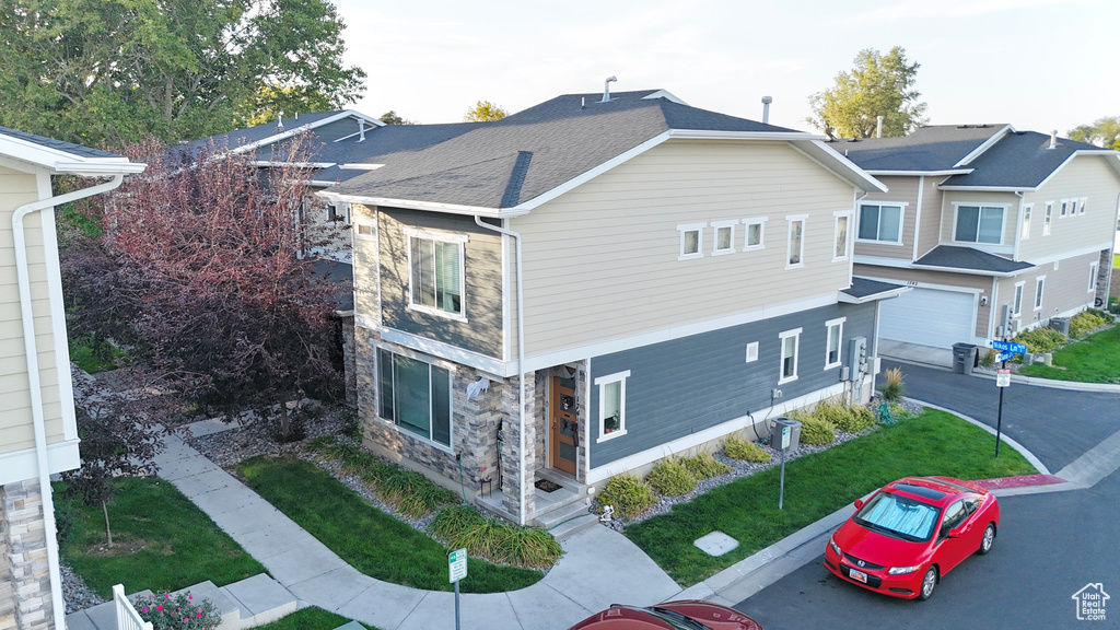 View of home\'s exterior with stone siding, a porch, a yard, and an attached garage