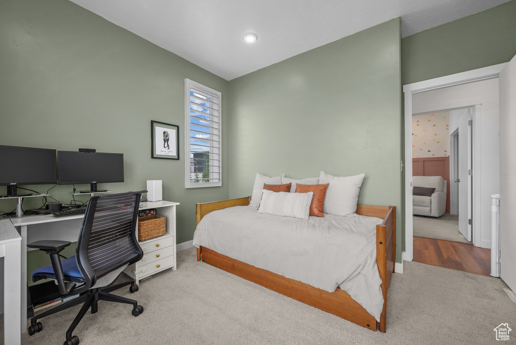Carpeted bedroom featuring a desk and baseboards