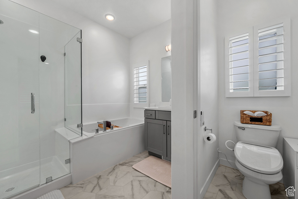 Full bathroom with marble look tiles, a stall shower, a garden tub, toilet, and vanity
