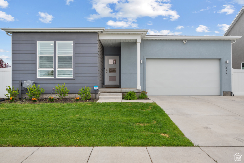 View of front of property with a front lawn, an attached garage, and driveway