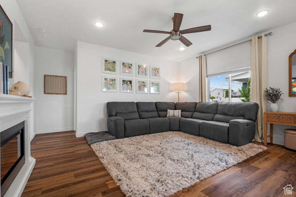 Living area with ceiling fan, dark wood-style flooring, a glass covered fireplace, recessed lighting, and baseboards