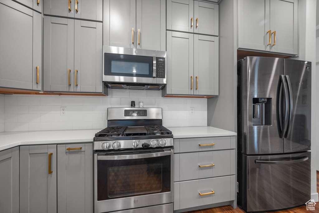 Kitchen featuring stainless steel appliances, gray cabinets, light countertops, and tasteful backsplash
