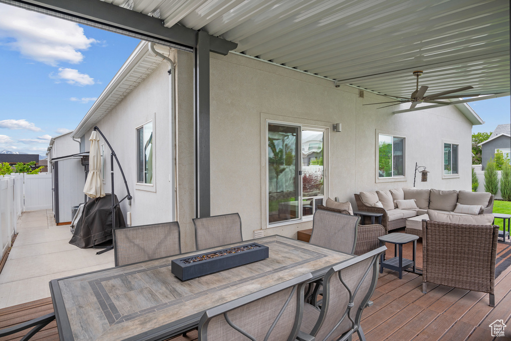 Wooden deck with an outdoor living space with a fire pit, ceiling fan, fence, and outdoor dining space