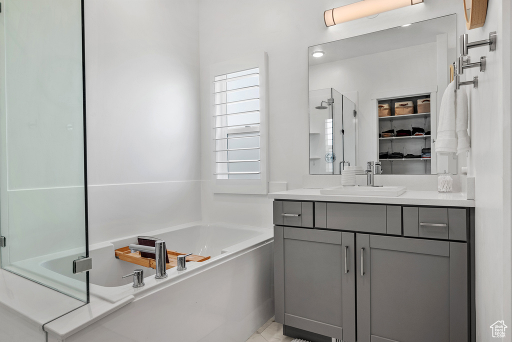 Full bath featuring a stall shower, a garden tub, vanity, and a spacious closet