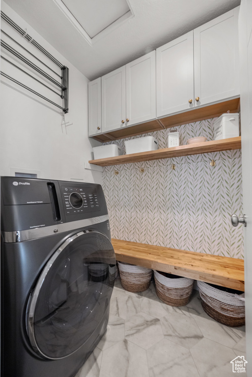 Clothes washing area with washer / dryer, cabinet space, marble finish flooring, and attic access