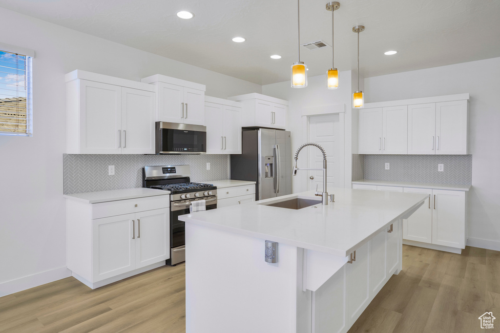 Kitchen featuring appliances with stainless steel finishes, a sink, light wood-type flooring, backsplash, and recessed lighting