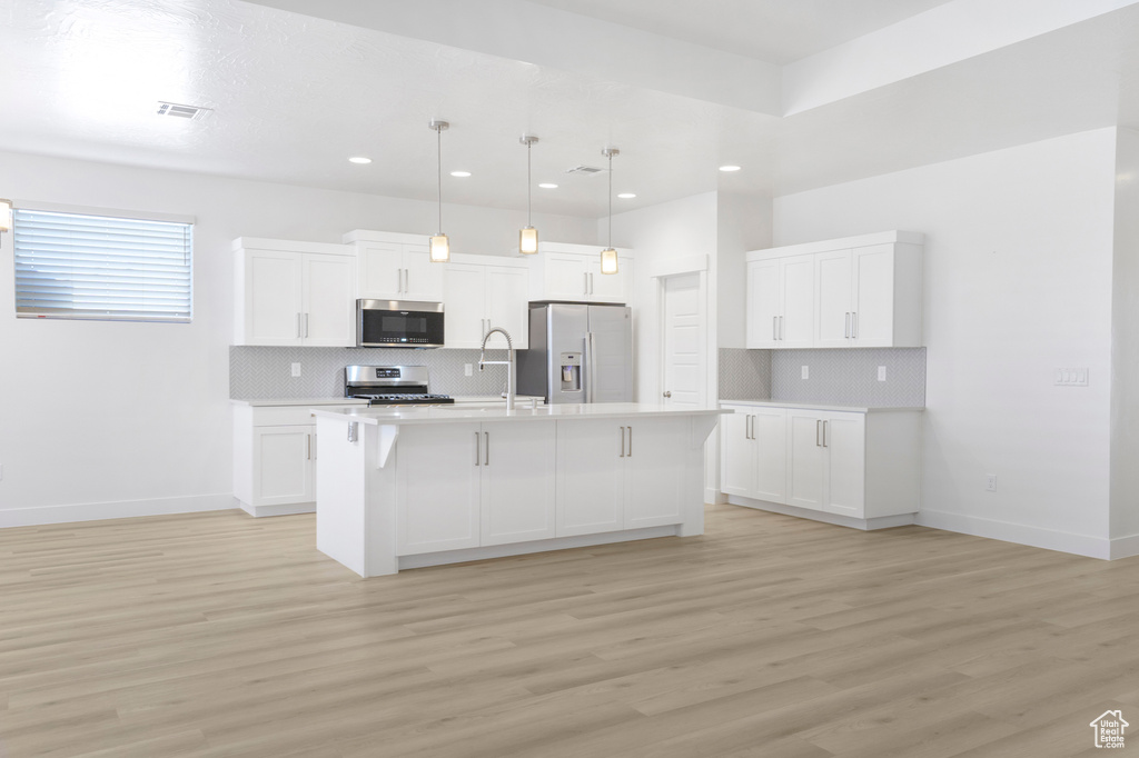 Kitchen with appliances with stainless steel finishes, a sink, backsplash, light countertops, and recessed lighting