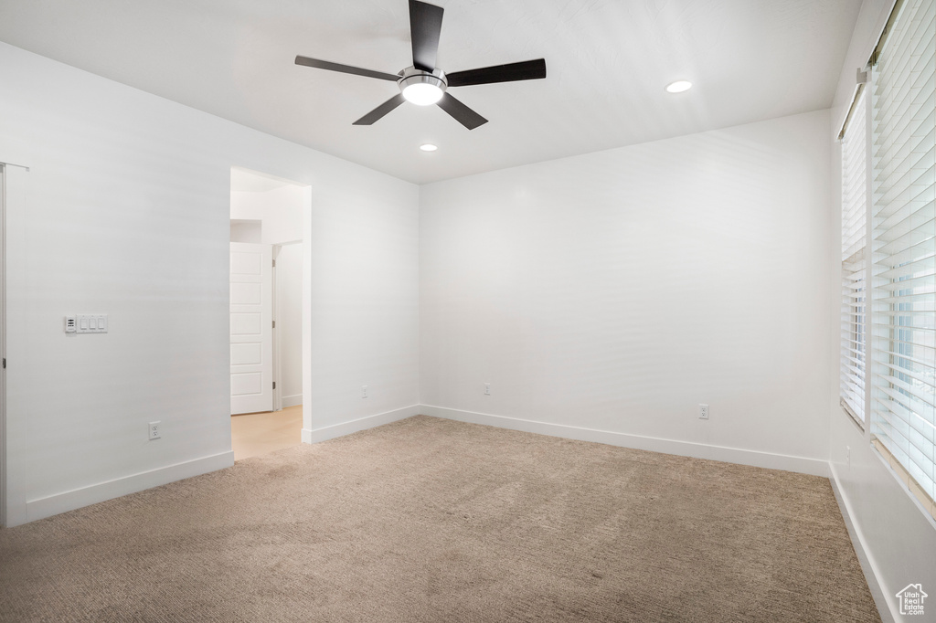 Spare room featuring light colored carpet, ceiling fan, baseboards, and recessed lighting