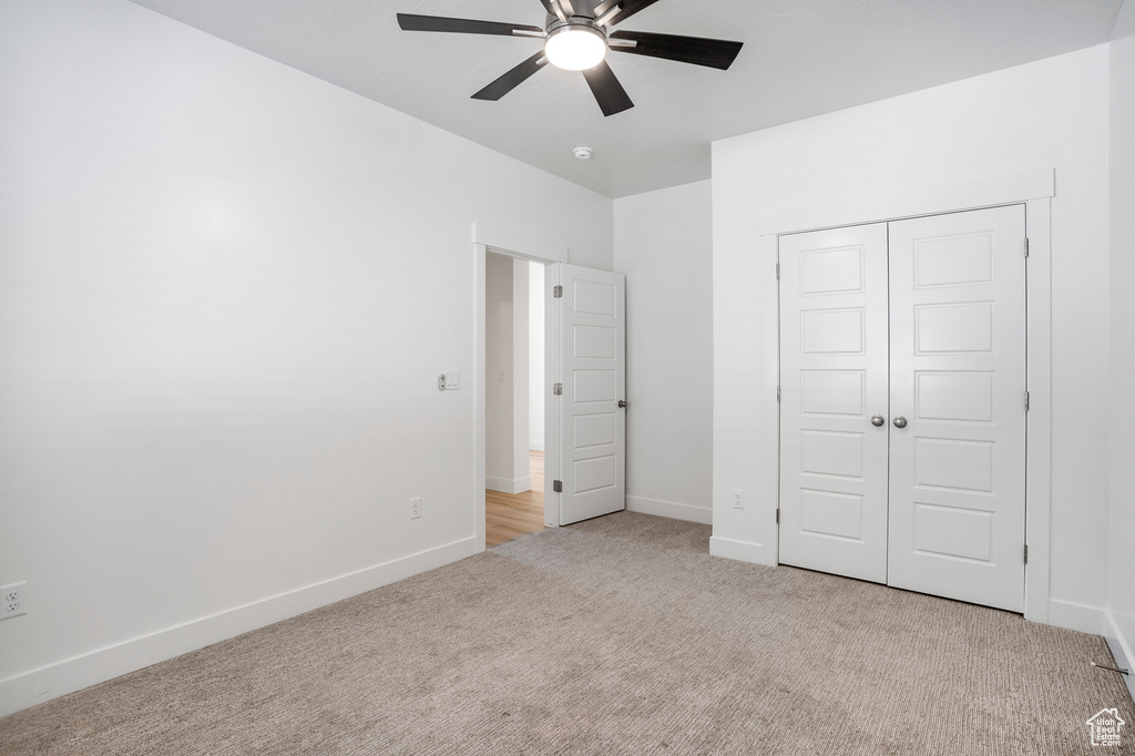 Unfurnished bedroom with light colored carpet, a closet, baseboards, and ceiling fan